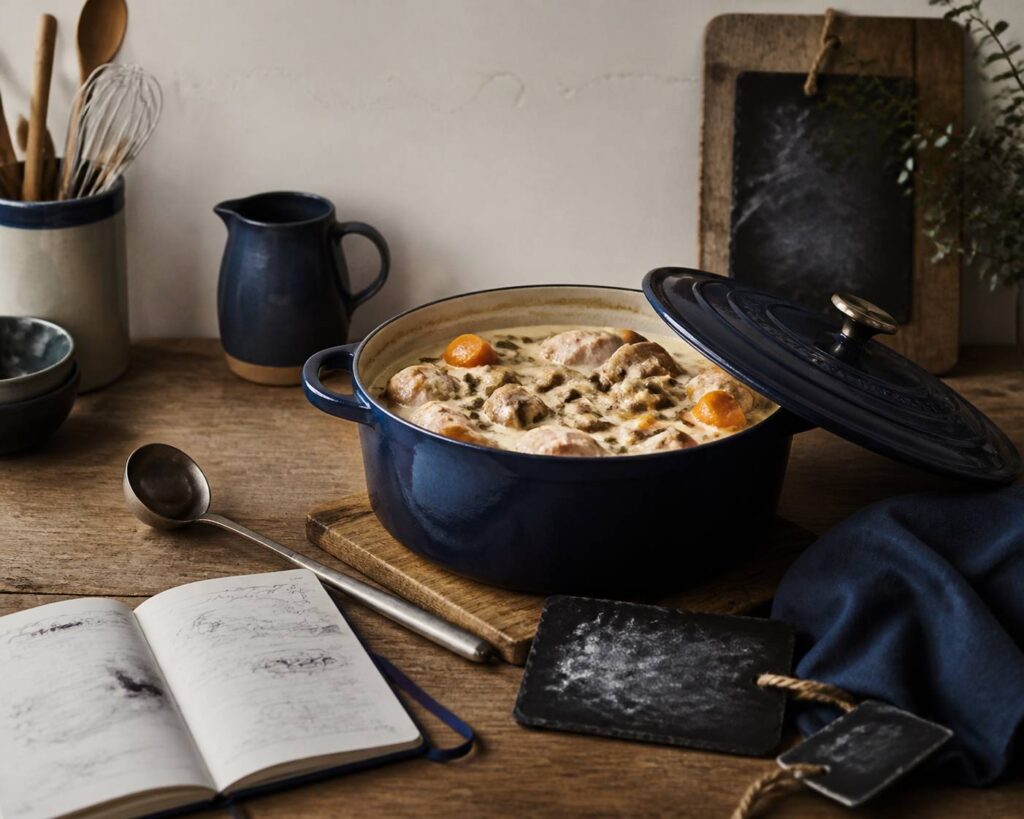 Cocotte ouverte de blanquette de veau à la sauce crémeuse avec carottes et champignons sur une table en bois