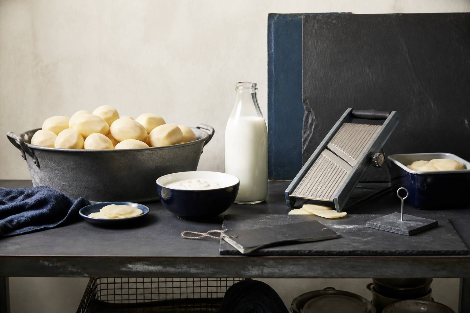Pommes de terre épluchées, bouteille de lait et bol de crème fraîche sur un plan de travail