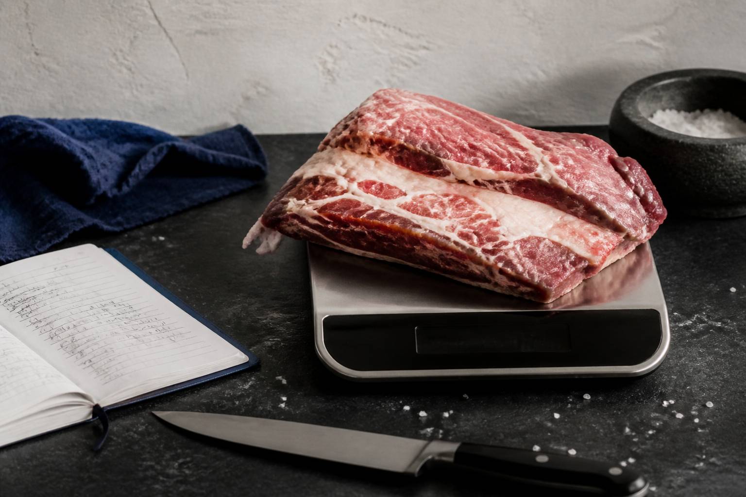 Morceaux de tendron de veau cru posés sur une balance de cuisine avec un carnet de relevé de prix