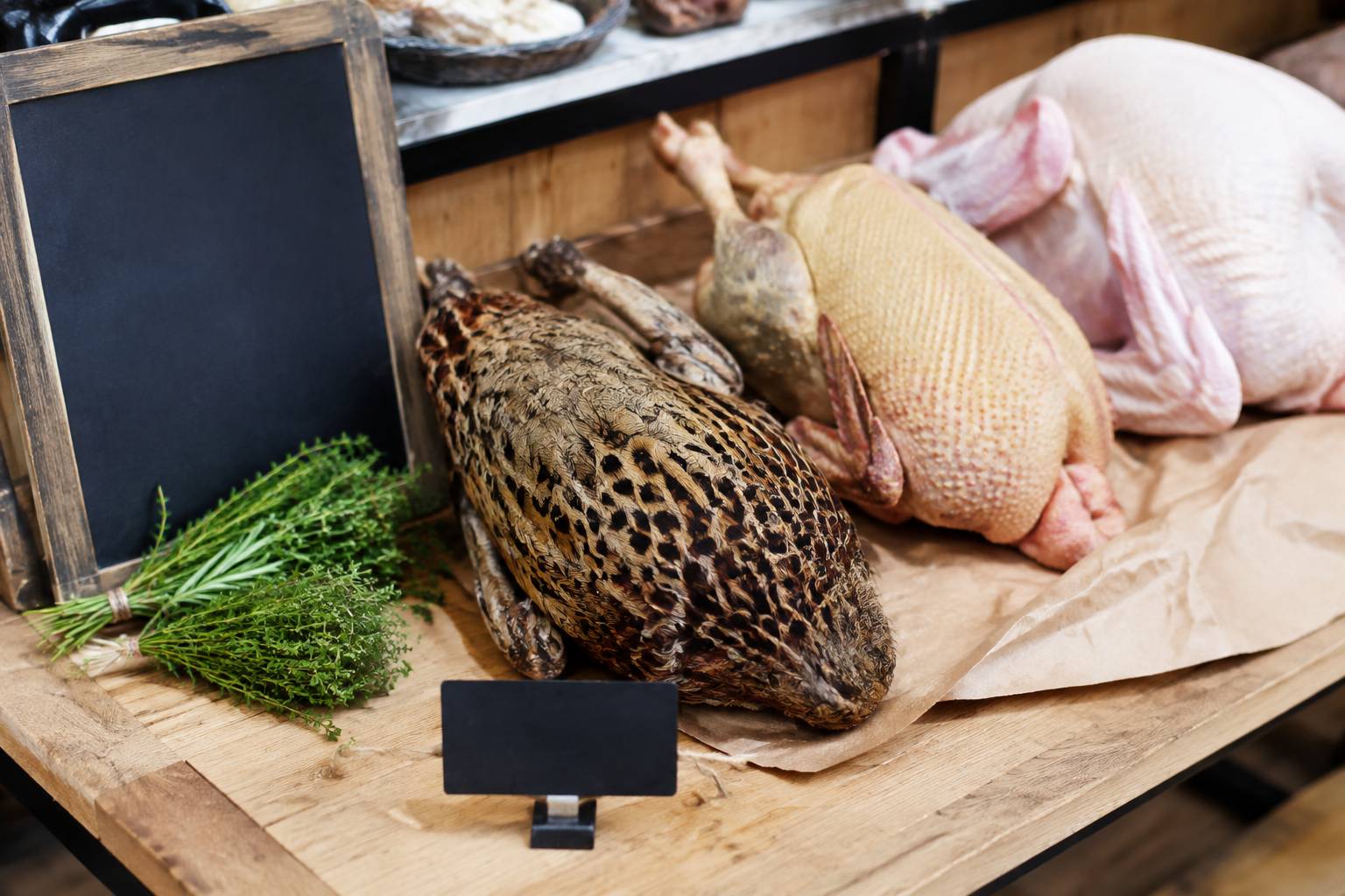 Étal de volailler présentant une poule faisane au plumage brun moucheté avec volailles fraîches