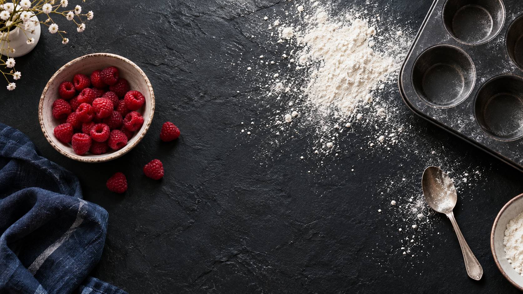 Framboises, farine et moule à muffins posés sur un plan de travail